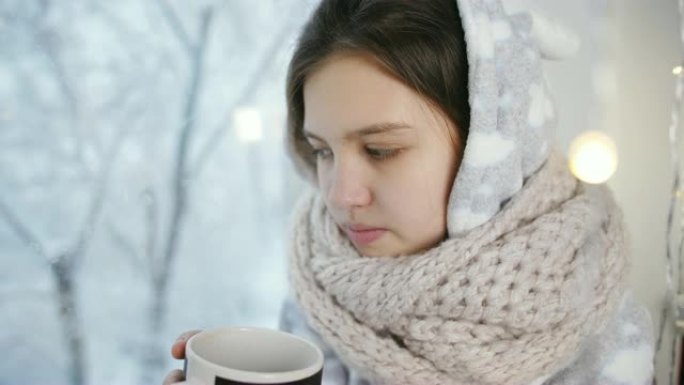 患病女孩少年冬天穿着我的睡衣，坐在窗前和越南热茶。
