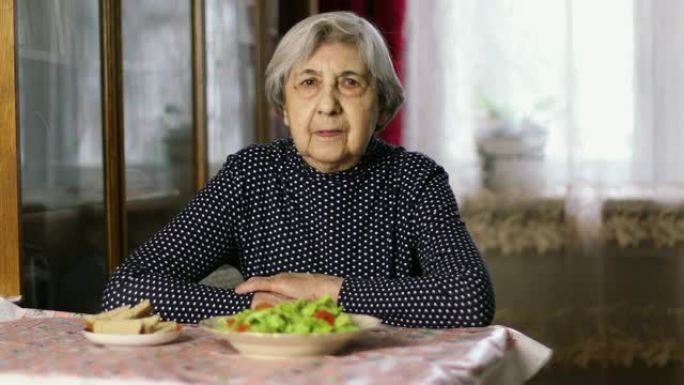 一位皱纹很深的老妇人正坐在餐桌旁等待午餐。