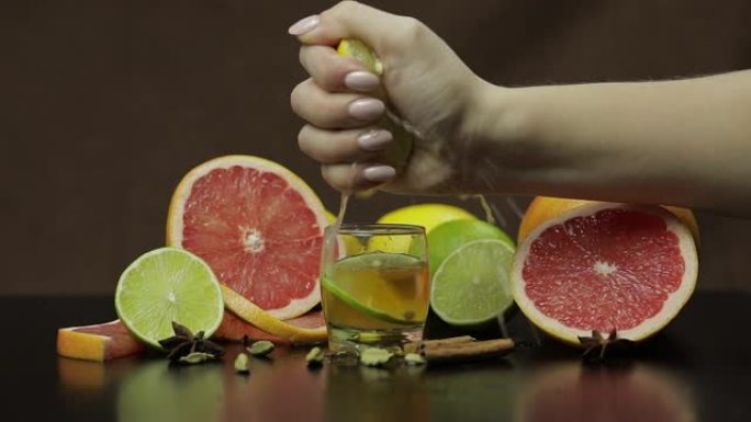 女人将柠檬中的果汁挤入装有酒精鸡尾酒的玻璃杯中