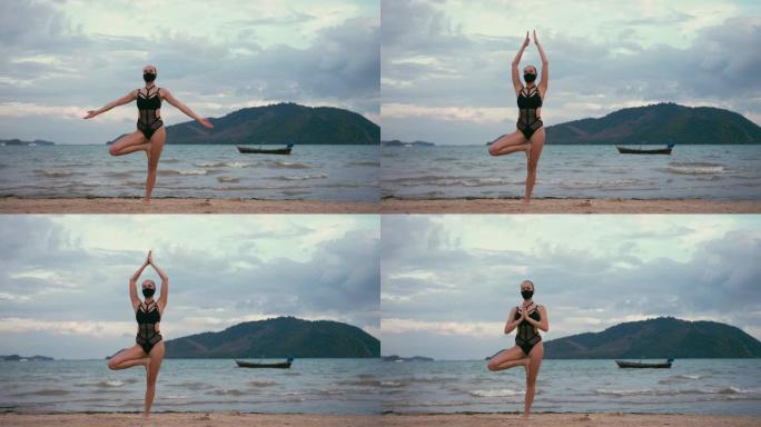 穿着黑色泳衣和医用防雾面具在海边练习瑜伽的白人妇女