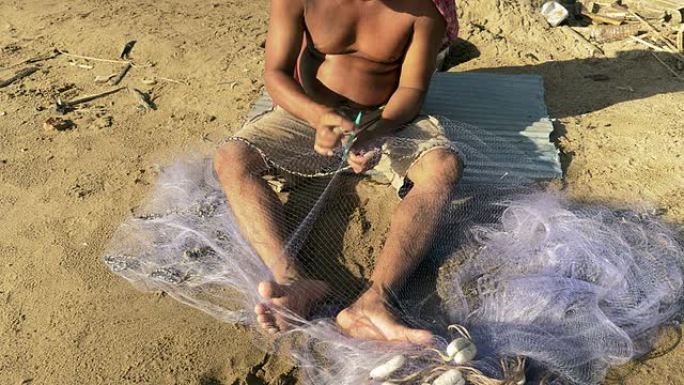 渔夫使用渔网针修补网