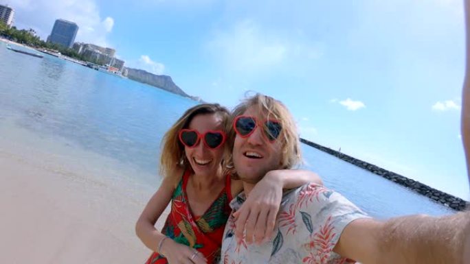 一对夫妇在夏威夷檀香山的威基基海滩自拍。威基基海滩的自拍视角广角。年轻夫妇用心形太阳镜自拍