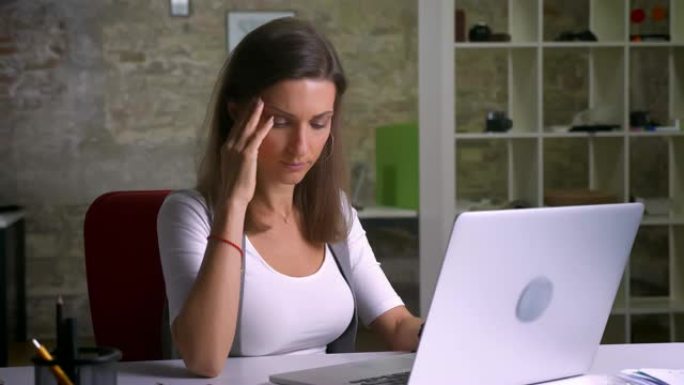 有吸引力的上班族在笔记本电脑上打字有麻烦和头痛