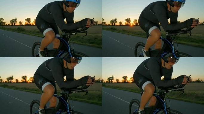 一名骑自行车的人在日落/日出时沿着乡间小路用力兜售。