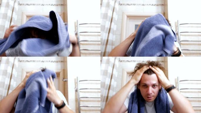 年轻的毛茸茸的男人用蓝色毛巾擦拭头发。