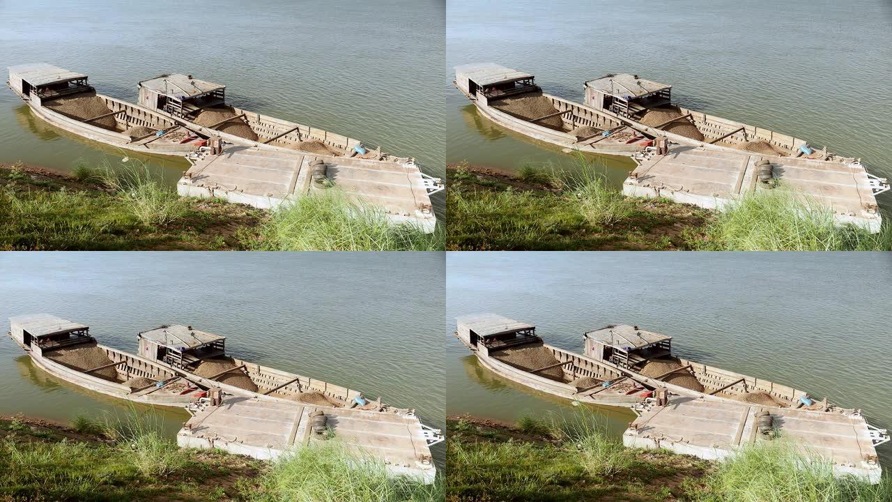 满载着疏浚的河沙和砾石的驳船并排绑在河岸上