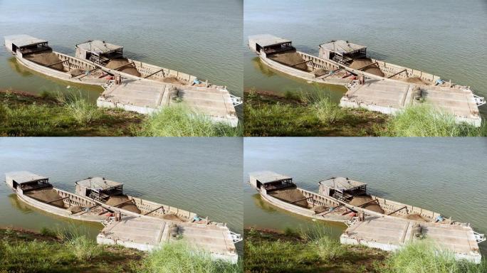 满载着疏浚的河沙和砾石的驳船并排绑在河岸上