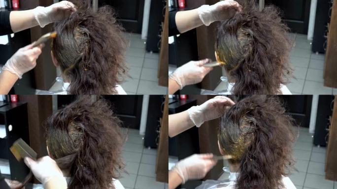 女美发师在理发店给女孩涂头发，然后涂上棕色油漆。头发护理。特写。后视图。4K。
