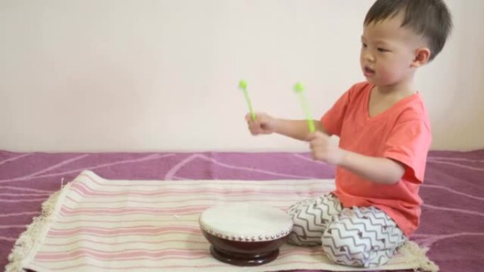 可爱快乐微笑的小亚洲2-3岁蹒跚学步男婴儿童握杆 & 演奏乐器鼓