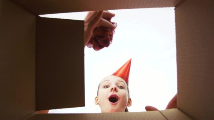 生日快乐女孩在派对帽打开礼品盒