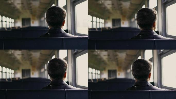 年轻人独自坐在UHD中通过移动的火车窗户看着风景