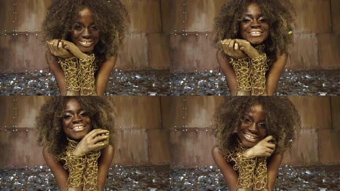 特写性感的非洲裔美国女模特与金色光泽的化妆品包围着银色的彩纸面部艺术。演播室背景
