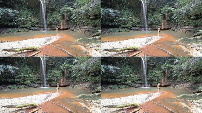 女人在马来西亚婆罗洲兰比尔山国家公园的雨林中游泳到一个迷人的五彩天然游泳池，瀑布风景秀丽。
