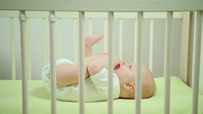 婴儿躺在家里的婴儿床里吃脚趾