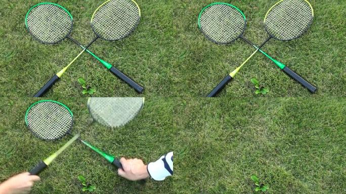 绿色夏日草地上的羽毛球拍。男女手拿球拍