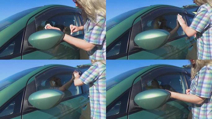 女孩用餐巾纸擦拭汽车玻璃。清洁和洗车