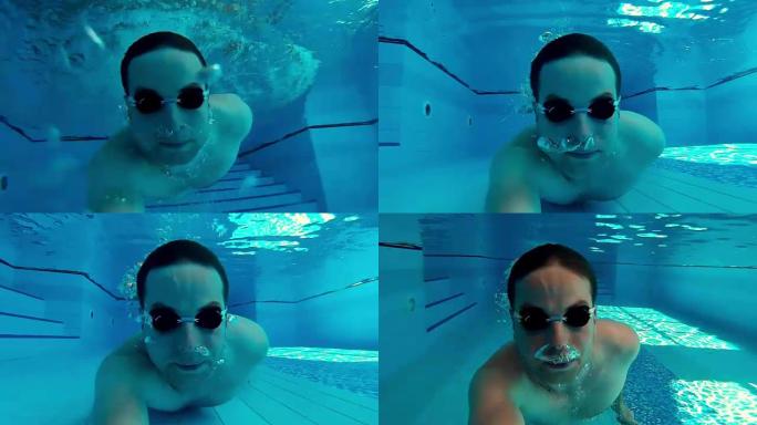 男子在阳光明媚的游泳池水下游泳