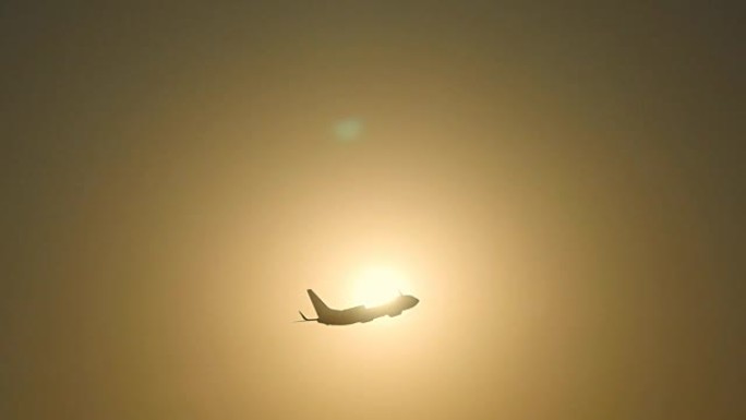 日落时，客机的轮廓飞过太阳。飞机在日出背景下起飞。飞机在美丽的早晨天空穿越日出。慢动作特写