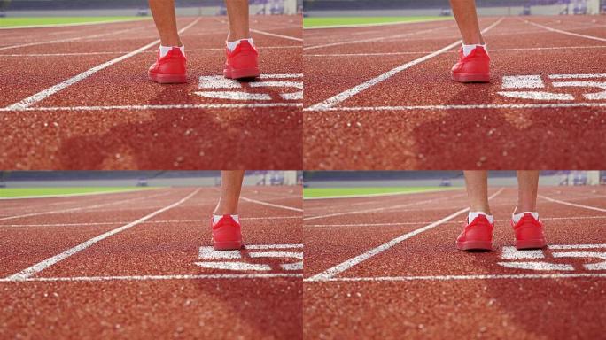 穿着红鞋的田径运动员在起跑线上热身