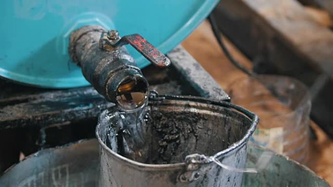 工人将机油或化学液体倒入旧的刮擦桶中