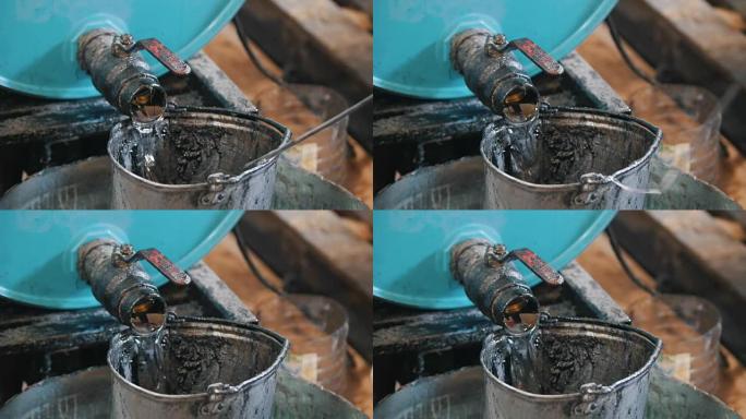 工人将机油或化学液体倒入旧的刮擦桶中