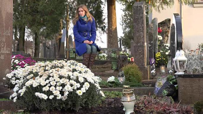 悲伤的女人坐在秋天的城市墓地的长椅上。FullHD