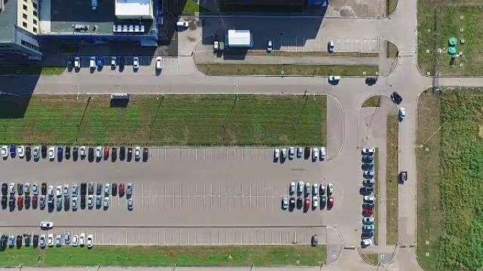 对工厂附近的停车场进行航测，周围是绿色的草坪。汽车在停车场上寻找停车位