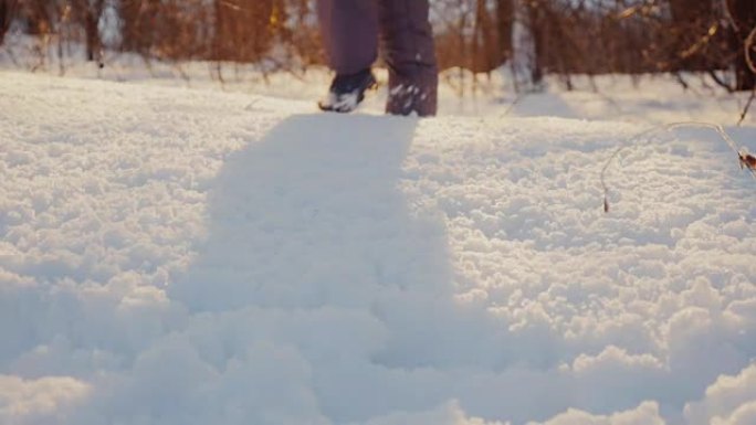 孩子的腿在夕阳下的初雪上。冬日欢乐