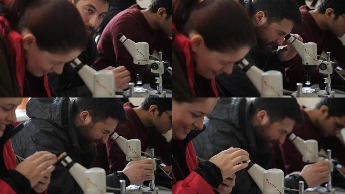 使用光学显微镜进行实践培训的学生在目镜上看，女人试图在电话上删除结果