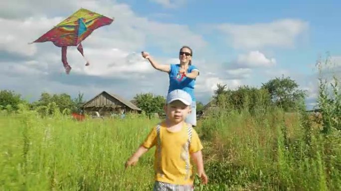 一位年轻的母亲带着婴儿在夏天在绿色的田野里发射空中风筝。母亲做得不好。儿子很开心