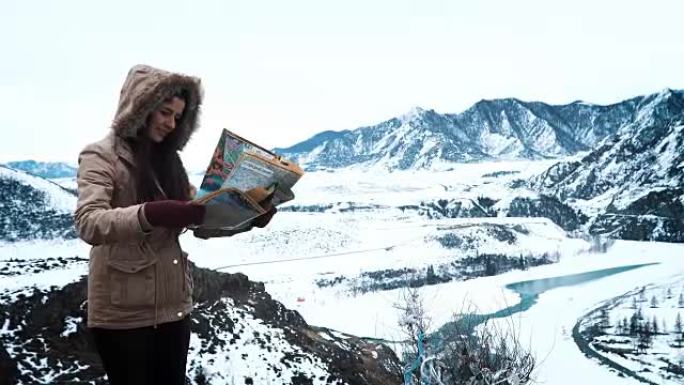 年轻旅游妇女在冬季山区旅游时探索山地地图，度假概念