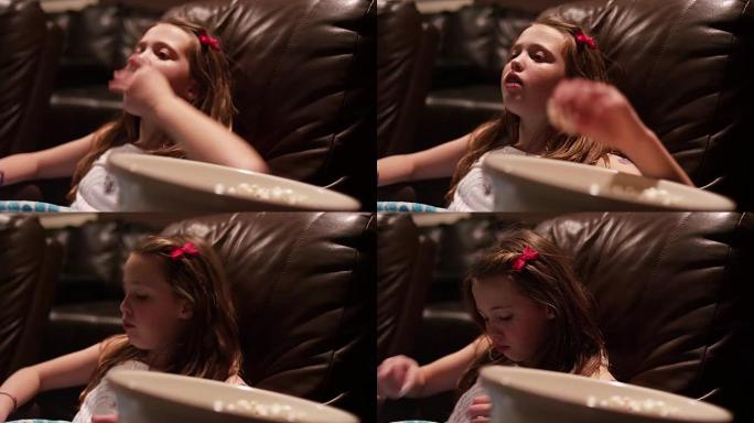 一个年轻的女孩在家庭影院看电影爆米花