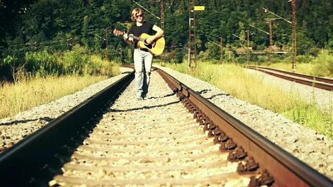 看起来很酷的左撇子长头发的家伙带着吉他沿着铁路走