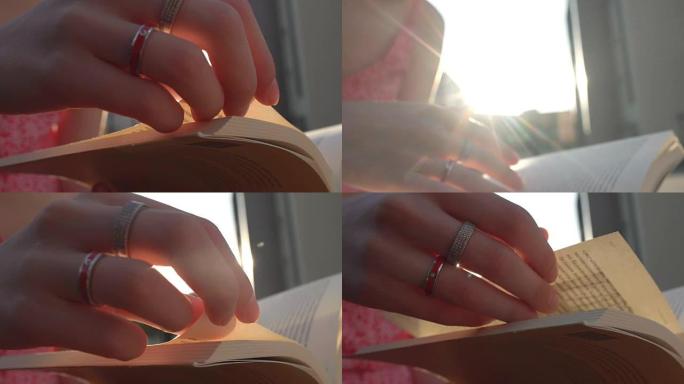 女人的手在日落时漂亮地翻过纸质书的书页