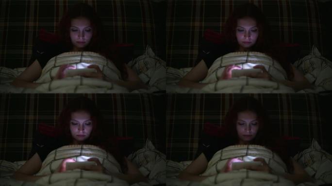 年轻女子晚上在家中躺在床上使用智能手机