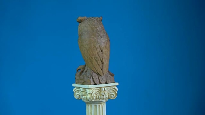 木制猫头鹰雕塑在古董柱模型上旋转，4K