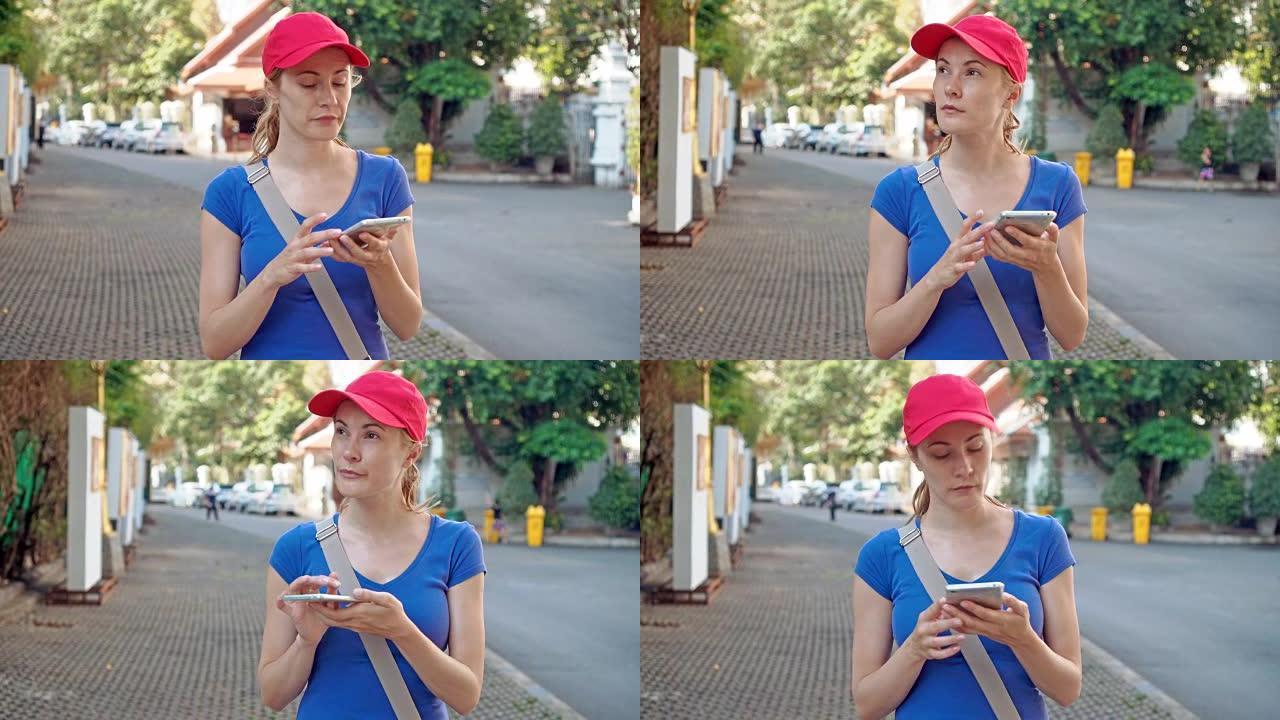 穿着红色帽子的迷人年轻旅游女性在智能手机上使用在线地图寻找正确的方向