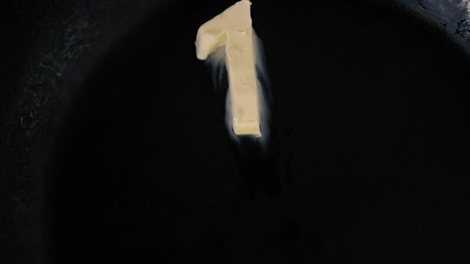 黄油在热锅上融化的第一形状-特写顶视图