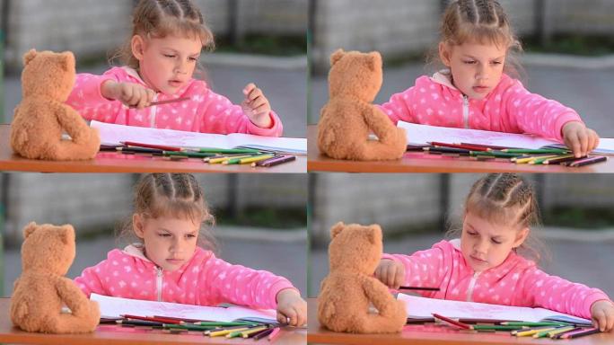 五岁女孩在相册中选择所需的彩色铅笔画