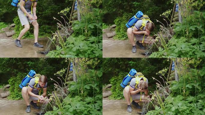 背着背包的疲倦旅行者从森林中的泉水中喝水