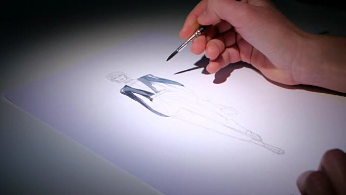 时装设计师用画笔画时装的草图。特写