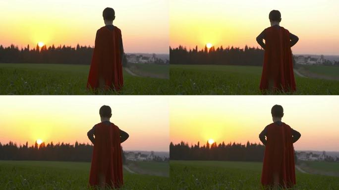日落时，一个在绿色田野里穿着超级英雄斗篷的男孩