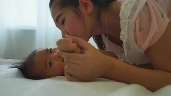 亚洲年轻漂亮的母亲用爱情慢动作亲吻她的小宝宝