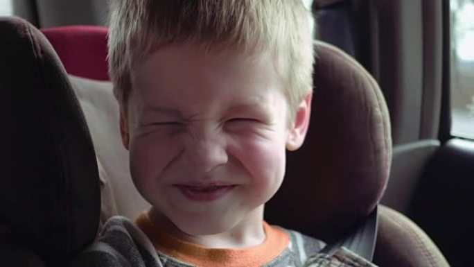 坐在儿童汽车座椅上的可爱男孩笑着笑