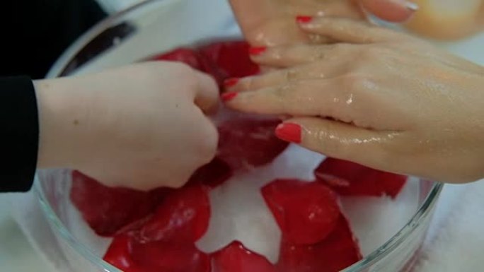 美甲师用花瓣冲洗女性的手