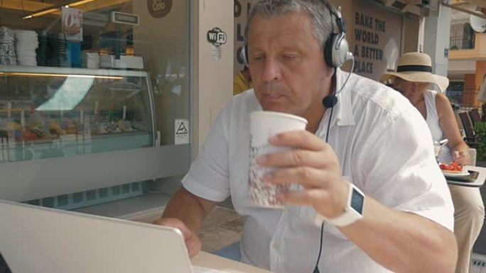 戴着耳机的男人在笔记本电脑上打字