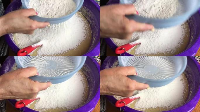 人的手在碗中通过筛子筛面粉。