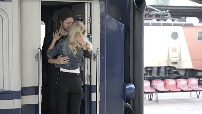 迷人的年轻女子在离开前在火车站与男友拥抱告别