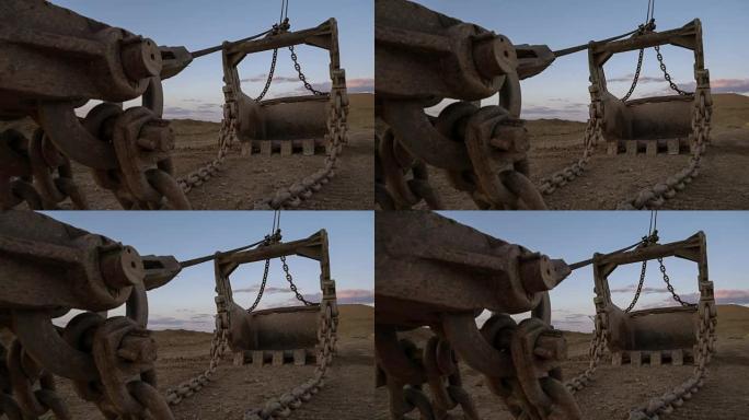 手持式PAN拍摄了15立方米拖铲挖掘机斗上巨大的铁链站在采石场边，映衬着夕阳下的蓝天。