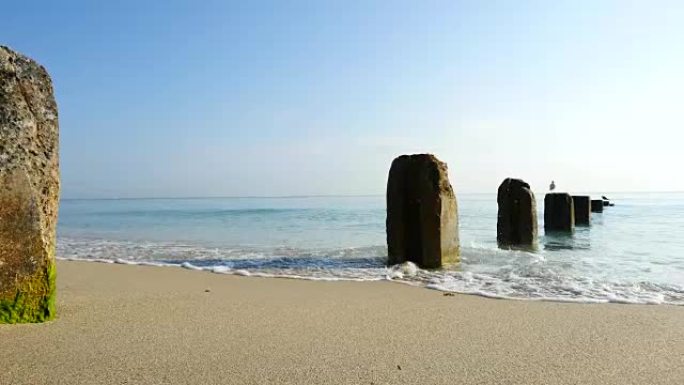 多莉拍摄了平静的海浪和平场景，用混凝土桩搭接在美丽的沙滩上